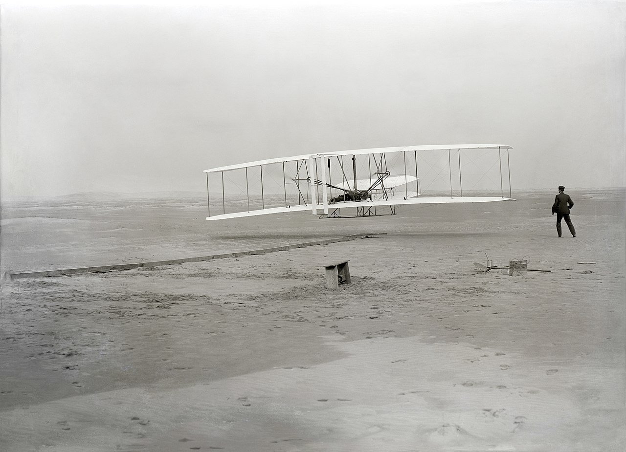 Wright Brothers first flight on December 17, 1903 at Kill Devil Hills, NC — Orville piloting the Wright Flyer as Wilbur runs alongside