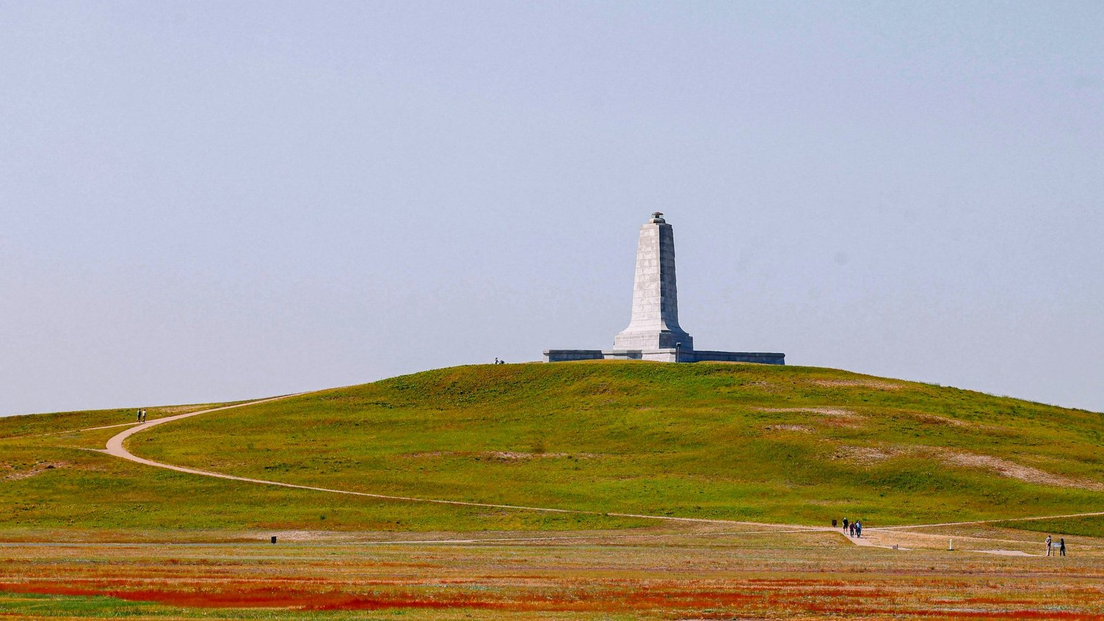 The granite Wright Brothers Memorial standing on the grassy crest of Kill Devil Hill in Kill Devil Hills, North Carolina, with a footpath curving up the hillside.