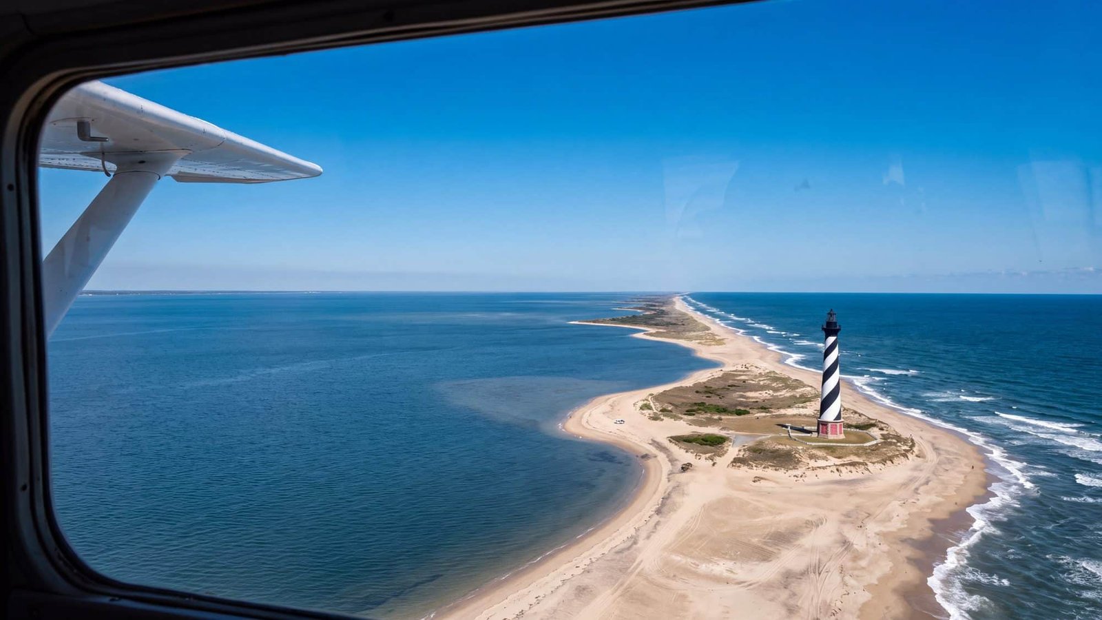 Aerial view from a small aircraft of the black-and-white spiral Cape Hatteras Lighthouse on the barrier island