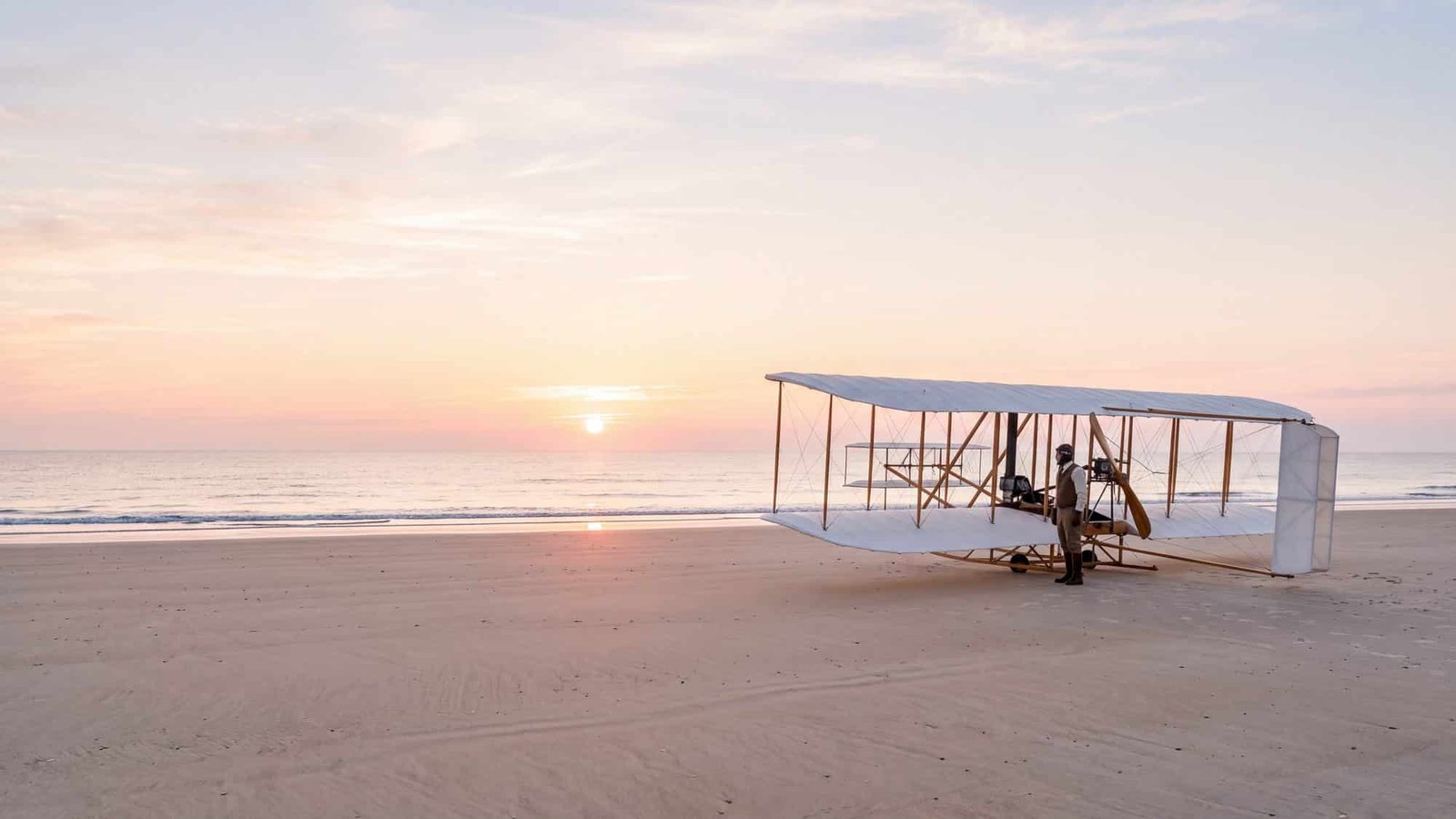 Replica early-1900s Wright biplane flyer on the sand at first light